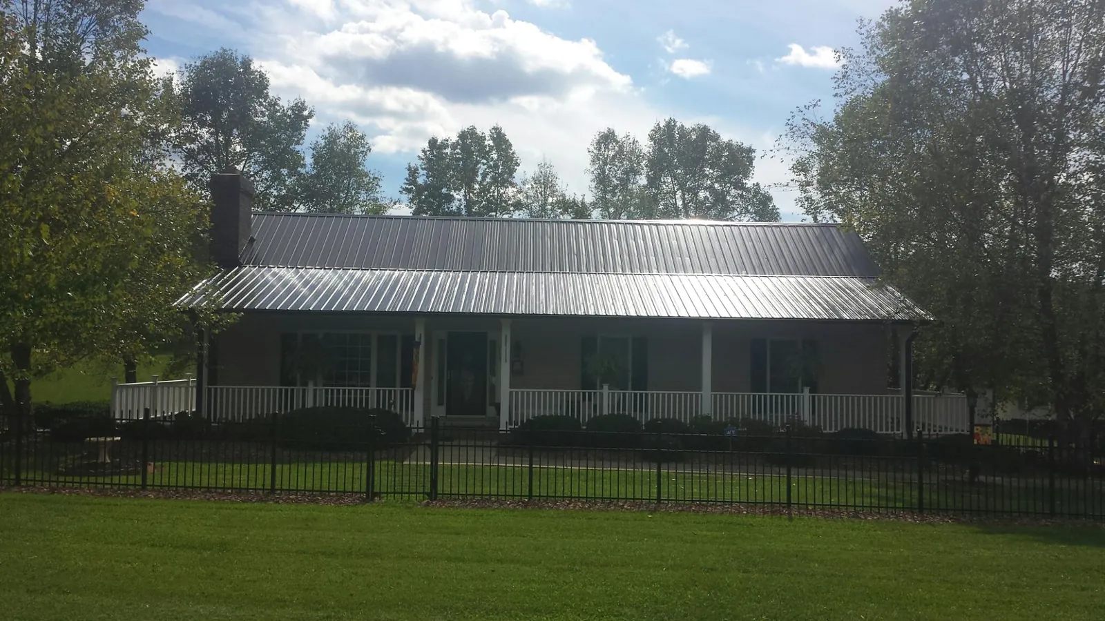 Gray metal roof on a brick ranch with a full width front porch — Gutter Guard Installation work by our crew in Port Orange
