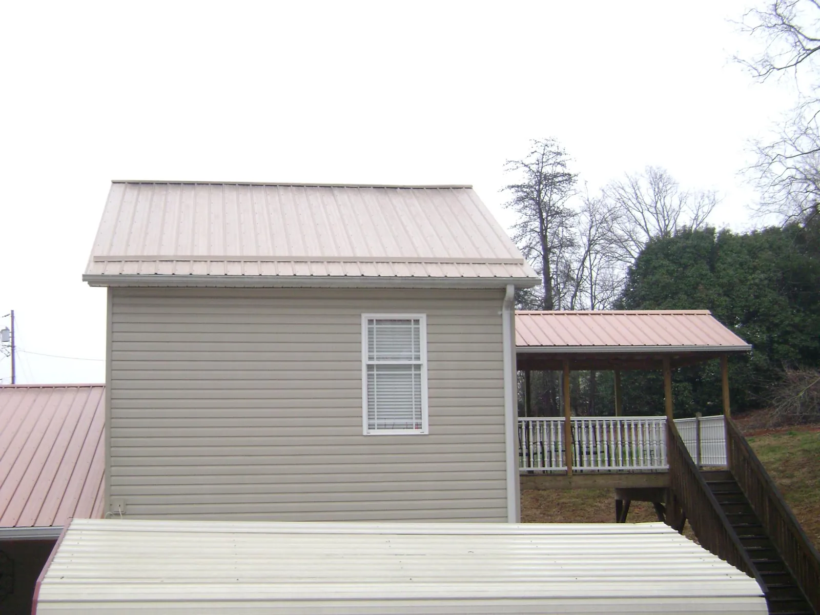 Tan metal roofs on a two story addition and attached porch, from a Roof Replacement job in Port Orange